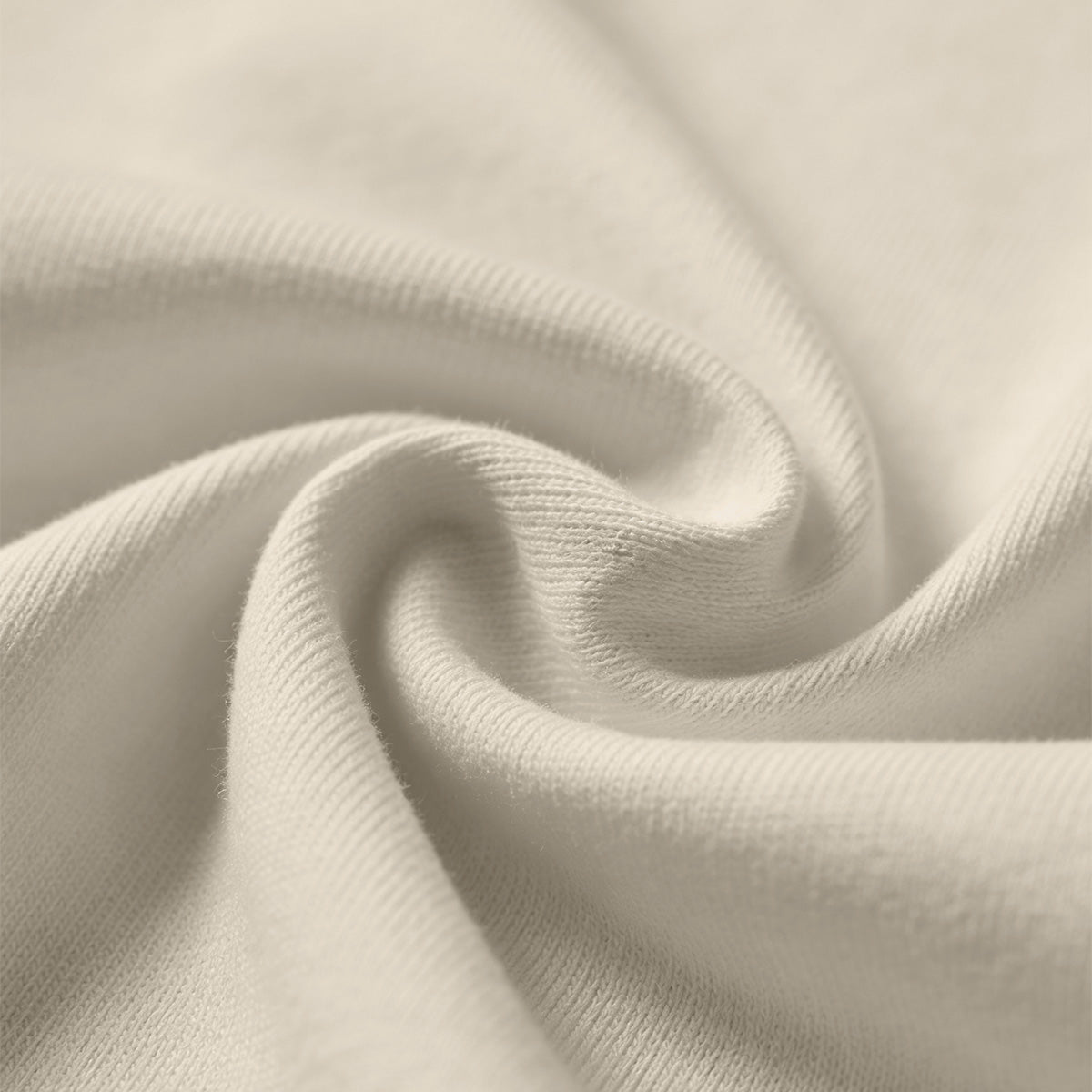 Soft beige fabric close-up showing a smooth, heavyweight knit texture with gentle folds and subtle draping.