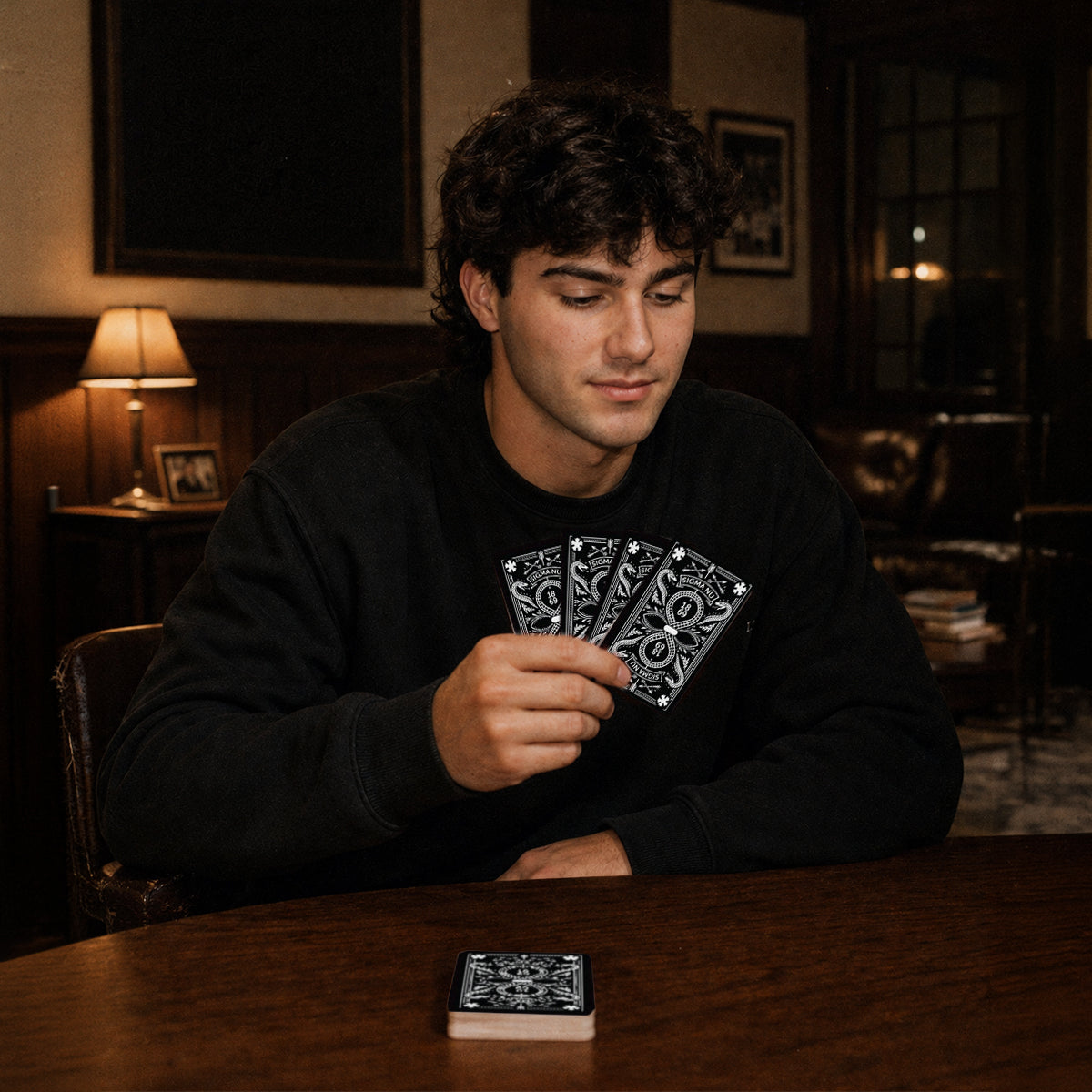 Fraternity brother holding custom Heritage Playing Cards during a poker game in a chapter house lounge.