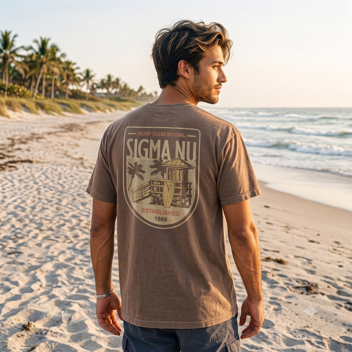 Model wearing the brown Surf Club Social T-shirt with a small front chest logo on a beach.