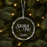 Limited Edition glass Christmas ornament with engraved design hanging on a decorated holiday tree